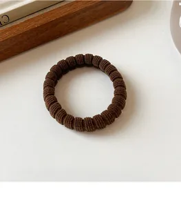 Close-up of a high-elasticity brown ribbed hair tie on a minimalist aesthetic background