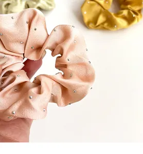 Gros plan détaillé d'un chouchou en satin rose orné de strass et d'une texture soyeuse