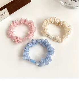 Vue détaillée de trois chouchous élastiques en rose, bleu et crème avec perles argentées