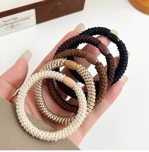 Close-up of woven high-elastic hair ties in neutral colors showing detailed texture