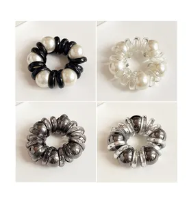 Detail view of four pearl spiral hair ties in black, clear, grey, and silver colors