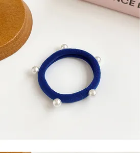 Détail d'un élastique bleu marine à haute élasticité orné de cinq perles blanches chic