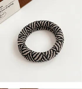 Macro view of thick knit checkered hair scrunchie with black and white woven texture