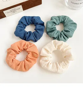 Detail view of 4-pack pleated scrunchies in blue, green, pink and beige fabric