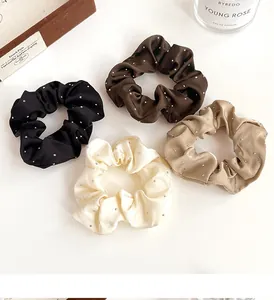 Détail de quatre chouchous en satin avec strass en noir, café, crème et kaki élégant