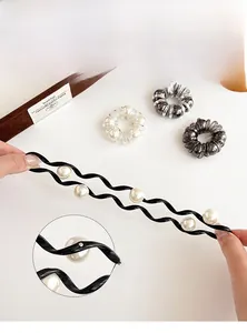 Detail display of hand-nailed faux pearls on a black wavy headband and hair ties