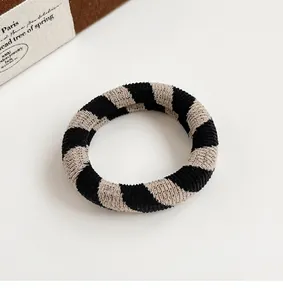 Detail of checkered elastic hair tie with durable knitted texture and soft beige stripes