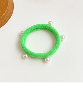 Gros plan sur un élastique à cheveux vert néon avec cinq perles nacrées élégantes