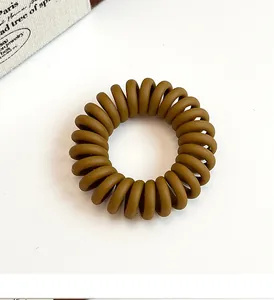 Gros plan détaillé d'un élastique spirale marron mat sur un fond blanc minimaliste