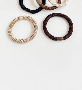 Detail of high-elastic braided hair ties in five earthy tones with oval resin buckles