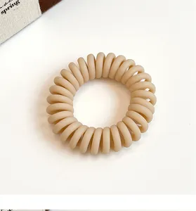 Gros plan d'un élastique spirale beige mat montrant la texture en résine et le design élastique