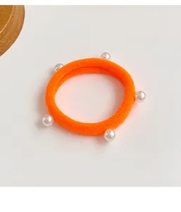 Vue rapprochée d'un chouchou orange fluo haute élasticité avec cinq perles blanches