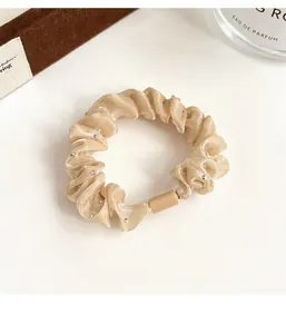 Détail d'un chouchou en satin champagne avec perles argentées sur fond élégant et raffiné