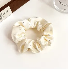 Gros plan d'un chouchou en satin crème orné de strass brillants avec une texture soyeuse