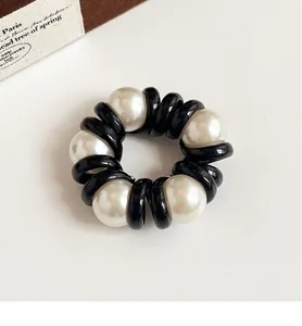 Detailed view of high-elastic black hair coil with elegant white pearl accents