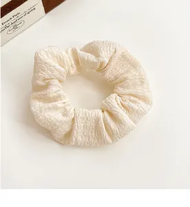 Detail of a creamy beige scrunchie with seersucker texture on a minimalist background