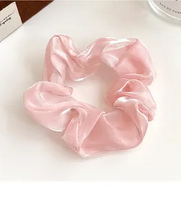 Gros plan sur un chouchou rose perle en tissu organza plissé avec texture satinée