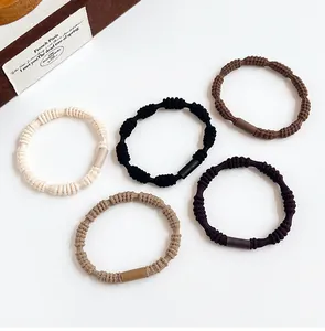Close-up of five elastic hair ties in neutral Morandi tones with textured knot design