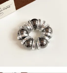 Detail of silver spiral phone cord hair tie with metallic beads on white background