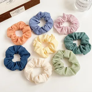 Set of 8 colorful seersucker scrunchies in pastel tones on a minimalist white desk