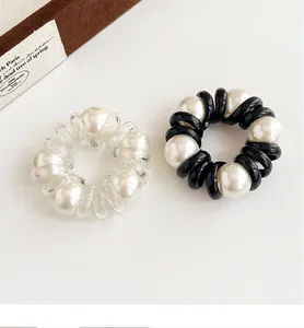 Detailed macro view of elastic spiral hair ties with large faux pearl embellishments