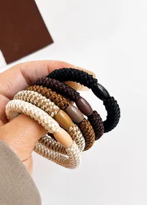 Close-up of thick braided high-elastic hair ties in neutral earth tones with plastic beads