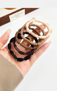 Close-up of five segment elastic hair ties in neutral tones held by a hand