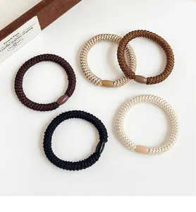 Close-up of five thick woven elastic hair ties in neutral tones on a clean background