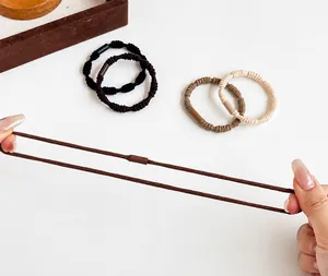 Detail showing the strong elasticity and stretch of multiple woven hair ties in neutral colors