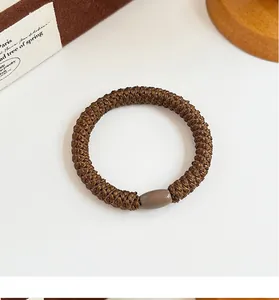 Detailed view of high-elasticity braided hair tie in dark brown with decorative bead