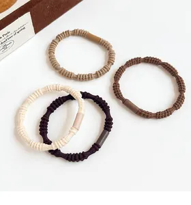 Detail of four high-elastic spiral hair ties in earth tones with cylinder connectors