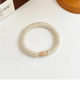 Detail of high-elasticity braided hair tie in beige with a smooth oval resin bead
