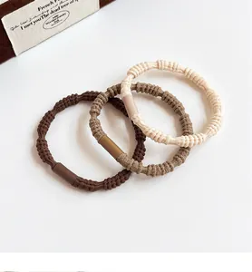 Close-up of three high-elasticity braided hair ties in coffee and cream tones