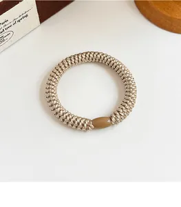 Close-up of beige woven high elasticity hair tie with a brown glossy oval decorative bead