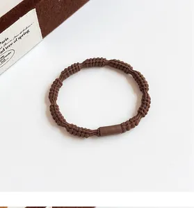 Detail of coffee-colored high elasticity hair tie with spiral woven texture and connector