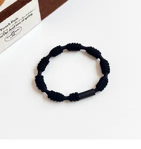 Detail of high-elastic black knotted hair tie with matte cylindrical connector