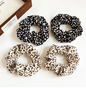 Flat lay of vintage leopard print scrunchies in cream and black fabric textures