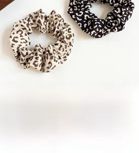 Detail shot of two leopard print fabric scrunchies with elastic texture and soft patterns