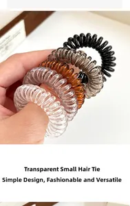 Detailaufnahme von fünf kleinen, transparenten Spiralhaargummis in neutralen Farben