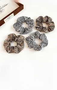 Detail of four leopard print scrunchies in brown and cream with a vintage jewelry box