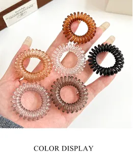 Nahaufnahme von sechs durchsichtigen Spiral-Haargummis in Braun, Bernstein und Rosa