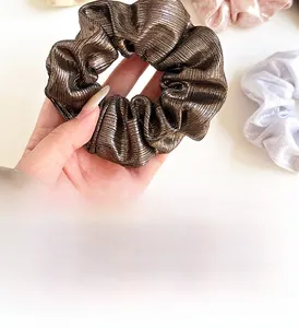 Détail de la texture plissée et du fini nacré des grands chouchous métalliques élégants