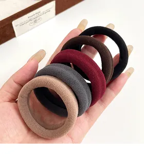 Détail d'élastiques à cheveux épais sans couture en cinq couleurs neutres tenus à la main