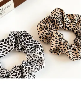 Detail of leopard print scrunchies in black-white and warm tones on a satin fabric