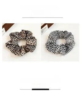 Detail of leopard print scrunchies in brown and black-white satin with pleated texture