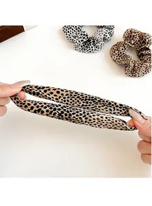 Close-up showing the elastic stretch of leopard print scrunchies in yellow and white fabric