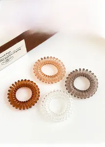 Makroansicht von transparenten und bernsteinfarbenen Spiralhaargummis in einer Box