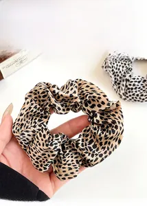 Close-up of leopard print scrunchies in yellow and white patterns with rich fabric texture