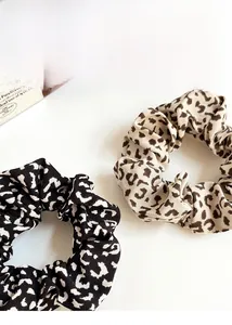 Detailed close-up of leopard print scrunchies in classic beige and black-white patterns