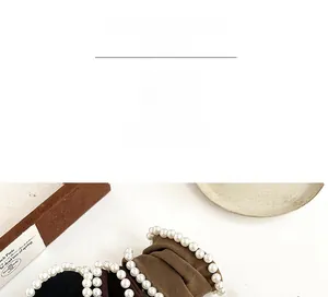 Close-up of wide velvet scrunchies with white pearls in navy blue and brown shades